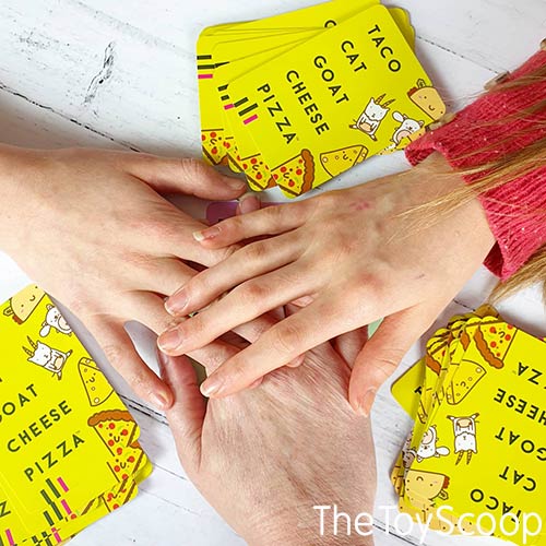Multiple hands slapping down on the central pile of Taco Cat Goat Cheese Pizza cards