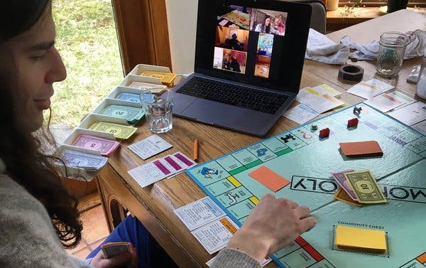 A laptop showing a video call with friends playing a card game, with cards visible on the table